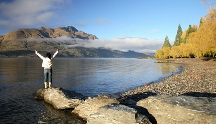 victorious woman standing-at new Zealand lake Queenstown